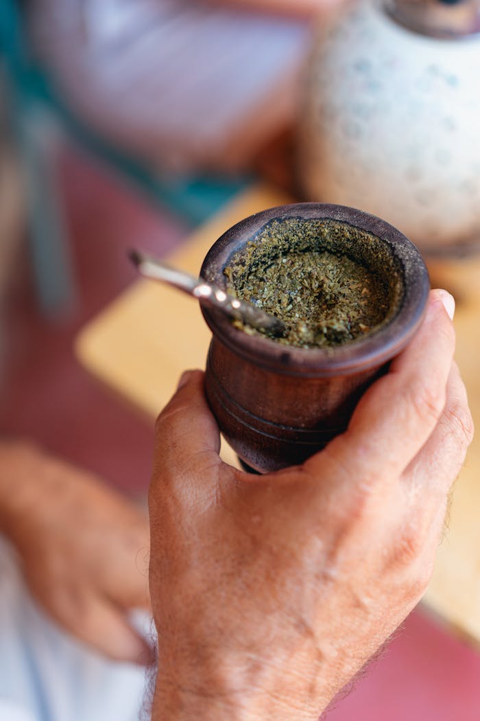 creative-01 Close-up of a hand holding a wooden cup of yerba mate, highlighting cultural tradition.